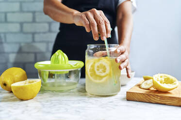 Die Hände einer Frau rühren frische Limonade um - KIJF03028