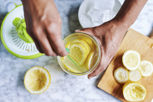 Die Hände einer Frau rühren frische Limonade um - KIJF03029