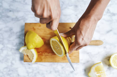 Hände einer Frau, die Zitronen auf einem Schneidebrett schneidet - KIJF03033