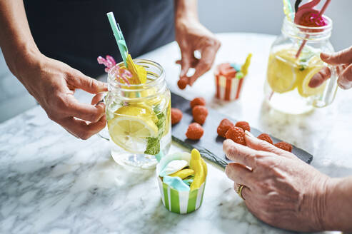 Hände zweier Frauen, die frisch gemachte Limonade genießen - KIJF03034