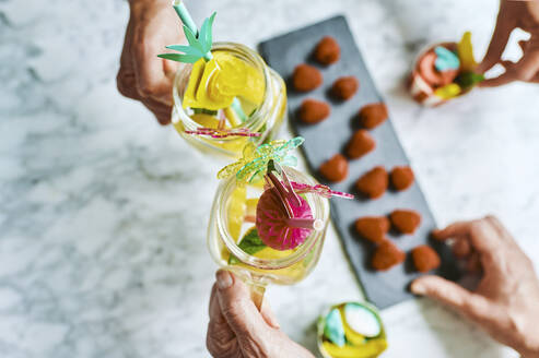 Hände von zwei Frauen, die mit Limonadengläsern anstoßen - KIJF03036