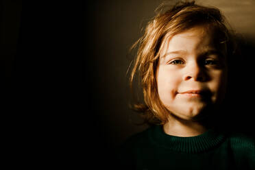 Determined toddler girl standing in bright light smiling - CAVF81992