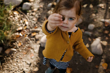 Junges Mädchen hält einen Stein hoch, der ihr Auge bei einem Sturz verdeckt - CAVF81995