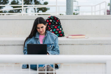 Young university student writes notes in her laptop on campus - CAVF82011