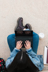 Draufsicht auf eine Studentin, während sie in ihren Laptop schreibt - CAVF82012