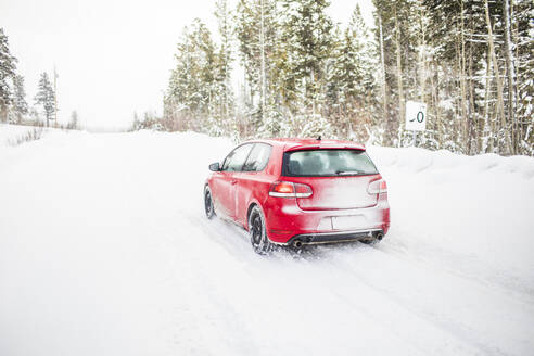 Rear view of red car driving on a snowy road. - CAVF82021