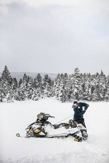 Ein Motorschlittenfahrer benutzt die Reißleine, um seine Maschine bei winterlichen Bedingungen zu starten. - CAVF82038