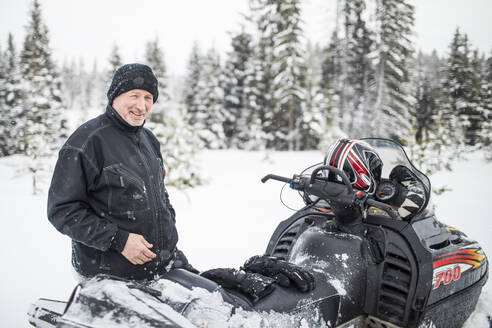 Porträt eines Mannes im Rentenalter beim Schneemobilfahren im Winter. - CAVF82039