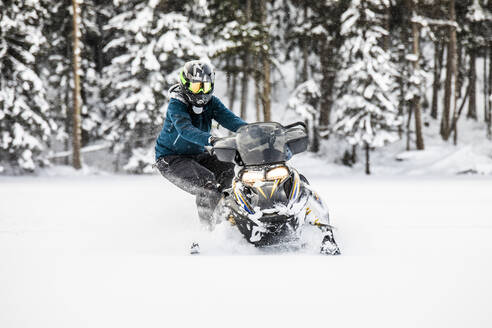 Ein geübter Motorschlittenfahrer steht auf der Seite und bereitet sich auf eine Kurve im Pulverschnee vor. - CAVF82042