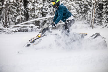 Seitenansicht eines Mannes, der mit dem Motorschlitten durch tiefen Schnee fährt. - CAVF82055