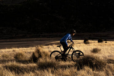 Frau silhouettiert Mountainbike während des Sonnenuntergangs - CAVF82105