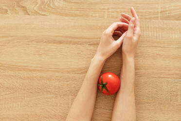 Saftige Tomate in Händen auf hölzernem Hintergrund tomato-ˈmätō,təˈmātō Перекл - CAVF82106