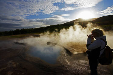 Ältere Frau fotografiert geothermischen Pool in Island - CAVF82137
