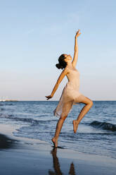 Delicate ballerina dancing on the beach at sunset - TCEF00674