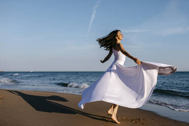 Ballerina in white dress dancing at the sea - TCEF00684