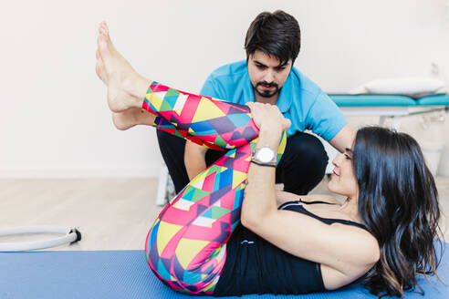 Ein sehbehinderter männlicher Physiotherapeut hilft einer Frau beim Training in einer Klinik - MRRF00055