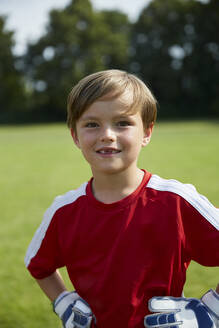 Portrait of happy boy in soccer uniform standing on field - AUF00504