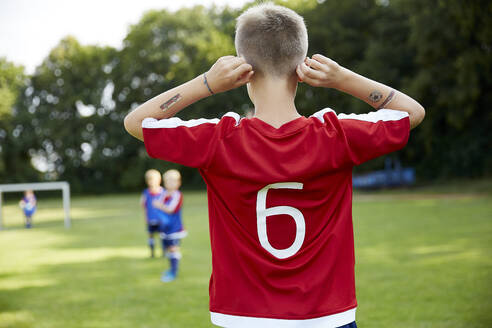 Soccer boy holding ears while standing on field - AUF00509