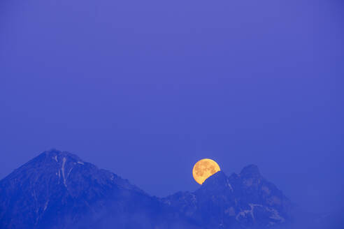 Deutschland, Bayern, Mond versteckt sich hinter den Gipfeln der Tannheimer Berge in der blauen Morgendämmerung - SIEF09860