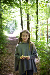 Porträt eines lächelnden Mädchens, das auf einem Wanderweg vor Bäumen im Wald steht - LVF08903