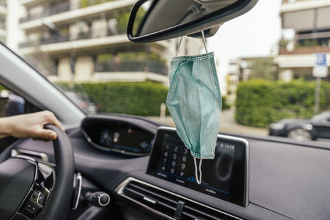 Schutzmaske hängt am Rückspiegel im Auto, lizenzfreies Stockfoto