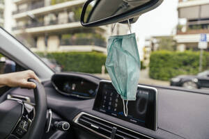 Protective mask hanging from rear-view mirror in car - MFF05612