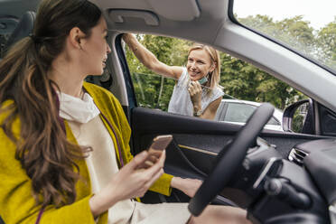 Two women talking through car window - MFF05617