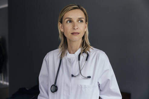 Porträt eines Arztes vor grauem Hintergrund mit Blick in die Ferne - MFF05618