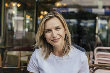 Portrait of smiling woman in front of a coffee shop - MFF05643