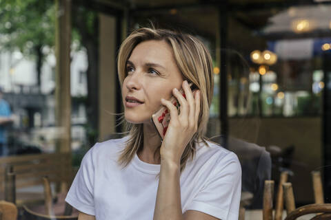 Porträt einer telefonierenden Frau vor einem Kaffeehaus, lizenzfreies Stockfoto