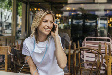 Portrait of woman on the phone with protective mask in front of a closed coffee shop - MFF05647