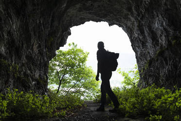 Mature male hiker walking while exploring cave - MCVF00393