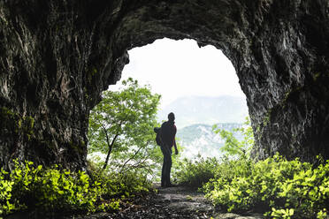 Male explorer standing at cave entrance - MCVF00394