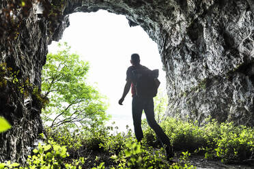 Älterer Mann erforscht beim Spaziergang inmitten von Pflanzen in einer Höhle - MCVF00395