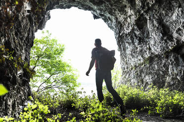 Mature man exploring while walking amidst plants in cave - MCVF00395