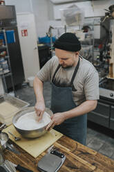 Männlicher Koch mischt Mehl in einer Schüssel in einer Großküche - PSIF00391