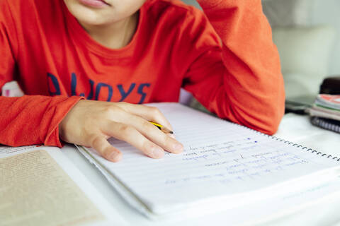 Boy studying from book while sitting at home stock photo