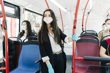 Porträt einer jungen Frau mit Schutzmaske und Handschuhen in einem öffentlichen Bus, Spanien - DGOF01038