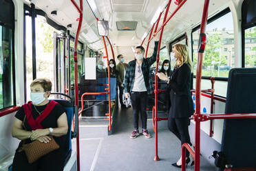 Fahrgäste mit Schutzmasken in einem öffentlichen Bus, Spanien - DGOF01074