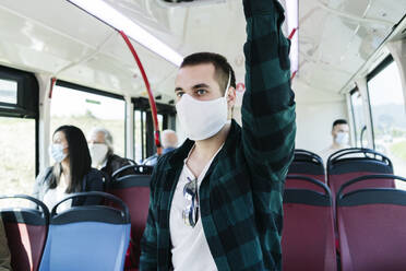 Porträt eines jungen Mannes mit Schutzmaske in einem öffentlichen Bus, Spanien - DGOF01075