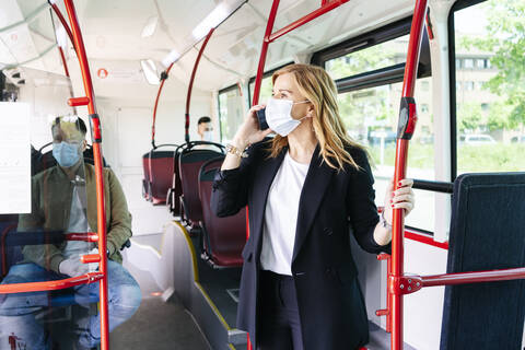 Businesswoman on the phone wearing protective mask in public bus, Spain stock photo