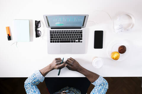 Junger Mann mit Laptop am Schreibtisch bei der Arbeit von zu Hause aus, lizenzfreies Stockfoto