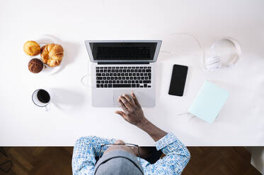 Junger Mann mit Laptop bei der Arbeit zu Hause - JCMF00770