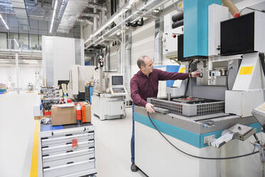 Man working at a machine in a factory - DIGF11418