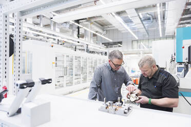 Two men examining product in a factory - DIGF11423