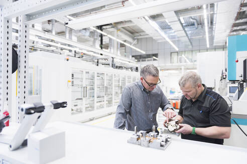 Zwei Männer begutachten ein Produkt in einer Fabrik - DIGF11423