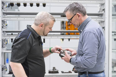 Two men examining product in a factory - DIGF11426