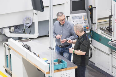 Two men talking at a machine in a factory - DIGF11437