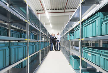 Three businessmen having a discussion in a factory storehouse - DIGF11501