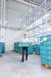 Man carrying a box in a factory storehouse - DIGF11512